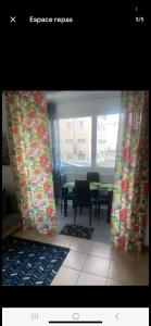 Habitación con mesa y ventana con cortinas. en Le Ti Coin à Didy, en Fort-de-France