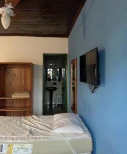 um quarto com uma cama e uma televisão na parede em Pousada da Rita em Lençóis