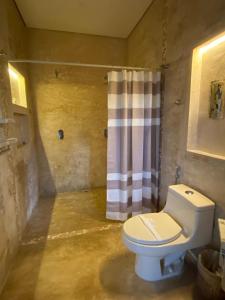 a bathroom with a toilet and a shower curtain at Hotel Para Ti - Adults Only in Holbox Island