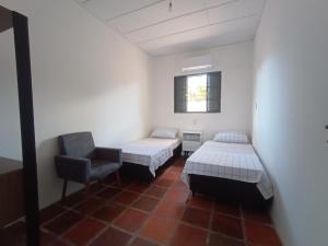 Habitación con 2 camas y una silla. en New hotel en Alegrete