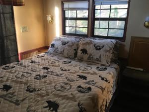 a bed with a comforter with cats on it at Cascades Inn - Cabin #2 - Full Kitchen in Tiger