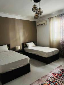 a bedroom with two beds and a window and a rug at Be my guest Apt/kafr abdo in Alexandria