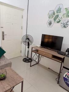 a living room with a television and a table with a fan at Honeydew Transient House in Mabiga