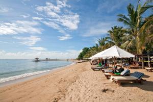 een strand met stoelen en parasols en de oceaan bij Jenna Residence Denpasar in Denpasar