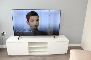 a flat screen tv sitting on a white dresser at Exquisite Stays Free parking, fast WiFi, close to city centre in Kenton