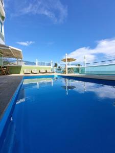 a swimming pool with blue water in front of a building at Hotel Aconchego Da Vila in Saquarema