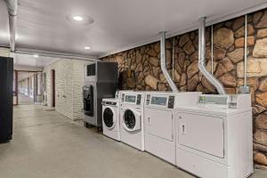 a laundry room with washing machines and a stone wall at Rodeway Inn in Dickson