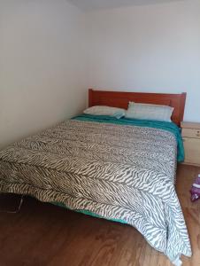 Una cama en un dormitorio con una manta de cebra. en Don Fernando, en El Quisco