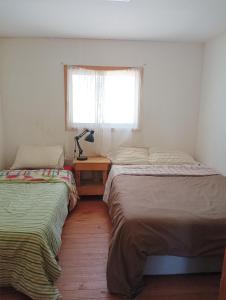 dwa łóżka w pokoju z oknem i stołem w obiekcie Don Fernando w mieście El Quisco