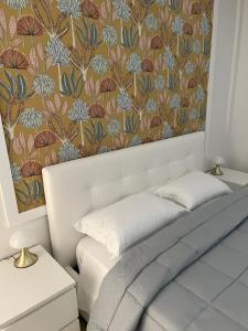 a bedroom with a white bed with a floral wallpaper at Casa Vacanze Le Tre Scimmiette Chic in Paterno