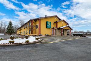 un grand bâtiment jaune avec un parking dans l'établissement Quality Inn, à Oneida