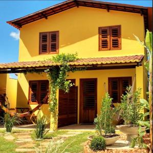 a yellow house with brown doors and windows at Pousada Meu Lugar in Jericoacoara