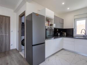 uma cozinha com armários brancos e um frigorífico de aço inoxidável em Apartments with a parking space Kastel Stari, Kastela - 22590 em Kaštela