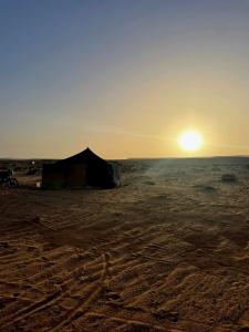 ein Zelt in der Wüste mit Sonnenuntergang im Hintergrund in der Unterkunft Aziz House 1 in Tan-Tan