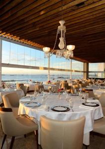 een restaurant met witte tafels en stoelen en een kroonluchter bij Ap com vista mar - Cloc Marina! in Salvador