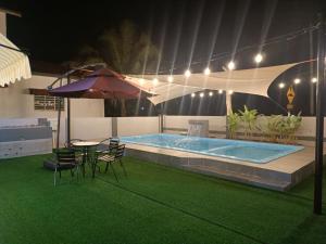 a pool with chairs and a table and an umbrella at AYRA HOMESTAY in Kuala Kangsar