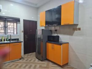 uma cozinha com armários laranja e um frigorífico de aço inoxidável em Prime PH Home em Port Harcourt