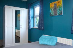 a blue bedroom with a bed and a window at Riverside Cottage in the Burren in Corrofin