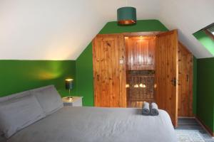 a bedroom with green walls and a bed with shoes at Riverside Cottage in the Burren in Corrofin