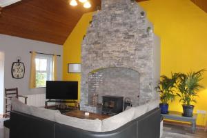 a stone fireplace in a living room with a tv at Riverside Cottage in the Burren in Corrofin