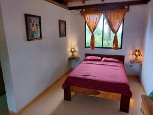 a bedroom with a bed with red sheets and two windows at Casa Ariana, Acepto Mascota in Ayampe