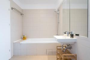 ein Badezimmer mit einer weißen Badewanne und einem Waschbecken in der Unterkunft Breeze - Lovely Apartment in Aviatiei with Parking in Bukarest