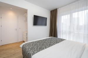 Schlafzimmer mit einem Bett und einem Flachbild-TV in der Unterkunft Breeze - Lovely Apartment in Aviatiei with Parking in Bukarest