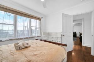 Un dormitorio blanco con una cama con toallas. en Long Island Beach House gateway to Mornington Peninsula #free parking, en Frankston