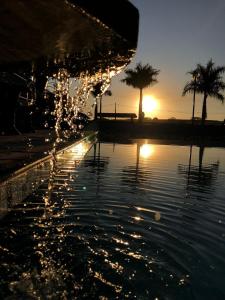 a pool of water with a sunset in the background at Pousada das Cores in Olímpia
