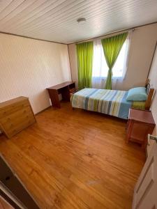a bedroom with a bed and a window and wooden floors at Casa Amoblada en Coronel 2 in Coronel