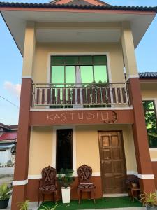 a house with a balcony and two chairs at Kastana Homestay II in Wakaf Baharu