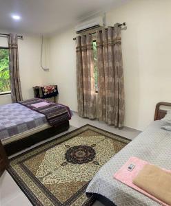 a bedroom with two beds and a rug on the floor at Kastana Homestay II in Wakaf Baharu