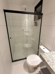 a bathroom with a toilet and a glass shower at Apê em condomínio, com Piscina, na melhor localização de Ilhéus in Ilhéus