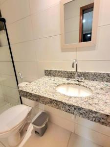 a white bathroom with a sink and a toilet at Apê em condomínio, com Piscina, na melhor localização de Ilhéus in Ilhéus