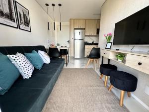 Apartamento novo decorado com sacada e linda vista da Cidade في ساو باولو: غرفة معيشة مع أريكة سوداء ومطبخ