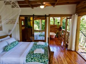 1 dormitorio con 1 cama y balcón con bañera en Jungle Spirit Treehouse, en Cahuita