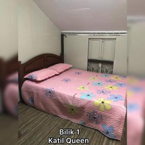 a bedroom with a bed with a pink comforter at Serambi Homestay Kangar in Kangar