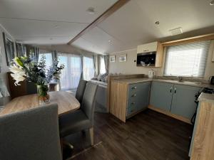 una cucina e una sala da pranzo con tavolo in una roulotte di 6 Berth Caravan With Stunning Sea Views And Decking To Relax On, Ref 32048az a Lowestoft