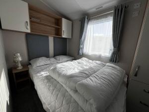 a bed in a small room with a window at 6 Berth Caravan With Stunning Sea Views And Decking To Relax On, Ref 32048az in Lowestoft
