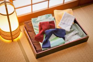 ein Koffer voller Kleidung und Krawatten auf dem Boden in der Unterkunft Ichinomata Onsen Grand Hotel in Shimonoseki