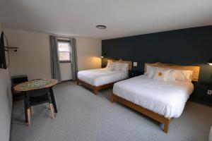 a hotel room with two beds and a table at East Rock Inn in Great Barrington