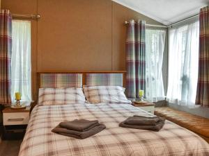 a bedroom with a bed with two towels on it at Woodland Lodge in Plumbland