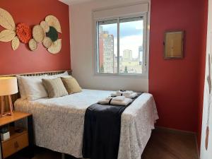 a bedroom with a bed with red walls and a window at Linda vista perto da Paulista com piscina/garagem in Sao Paulo