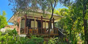 a house with a porch in the middle of trees at Ananda B&B in Gili Islands