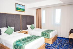 2 camas en una habitación de hotel con detalles verdes en UB Grand Hotel, en Ulán Bator
