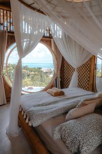 a bedroom with a canopy bed with a large window at Camanta Penida - Adult Only in Nusa Penida