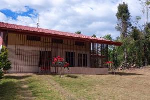 ein Haus mit roten Blumen davor in der Unterkunft Villa El Sol in Jardín