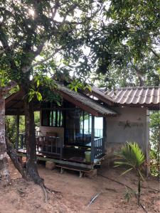 uma pequena casa com um alpendre e uma árvore em The Big House em Koh Chang Ranong