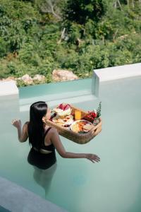 a woman sitting on a ledge with a basket of food at Camanta Penida - Adult Only in Nusa Penida