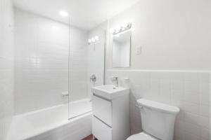 a white bathroom with a toilet and a sink at Epic Furnished Private Room With Shared Bath in Philadelphia